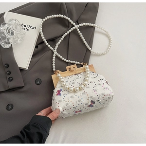 Detailed shot of beaded crossbody shell bag with sequin butterfly and pearl strap