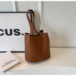 Vue détaillée du sac seau en cuir marron foncé avec rivets dorés et logo de la marque
