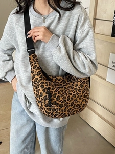 Leopard print crescent crossbody bag with adjustable wide strap shown on a model
