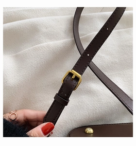 Close-up of dark brown leather shoulder strap with adjustable gold buckle detailing