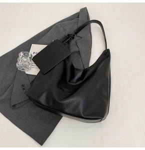 Détail du sac hobo en cuir noir grainé avec bandoulière nouée et petite pochette assortie