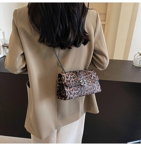 Détail du sac bandoulière léopard avec clous argentés et chaîne en métal sur modèle