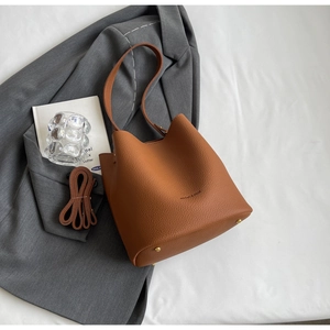 Détail du sac seau caramel avec cuir grainé litchi et logo embossé sur le devant