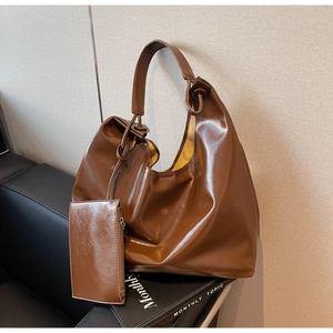Detail of dark brown glossy leather tote bag with a small matching pouch on a chair
