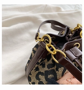 Detailed macro view of leopard print canvas bucket bag with premium brown leather trim
