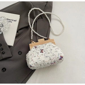 Detail of canvas shell bag with sequined butterfly and white pearl bead strap on a suit