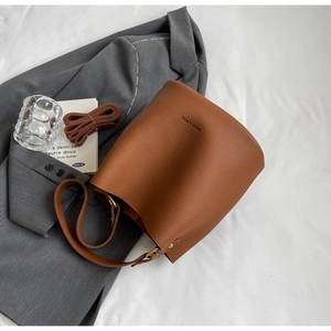 Détail du sac seau marron avec texture litchi et bandoulière amovible incluse