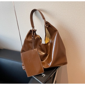 Detail view of dark brown oil-wax leather tote bag with matching zipper pouch accessory