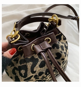 Detail of leopard print bucket bag featuring woven texture and brown leather drawstring