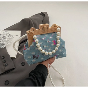 Detail of blue denim shell bag with sequin butterflies and vintage wood frame