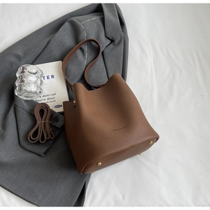 Détail d'un sac seau marron en cuir grainé avec des pieds de protection en métal doré