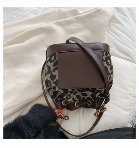 Detail of leopard print fabric texture and dark brown leather trim on the bucket bag
