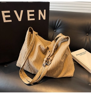 Detail der khakifarbenen Plissee-Tasche mit Silberschnalle auf schwarzem Ledersofa