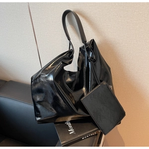 Detail of glossy black patent leather shoulder bag with matching mini zipper pouch