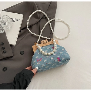 Detail of blue denim shell bag with butterfly sequins and pearl beaded straps