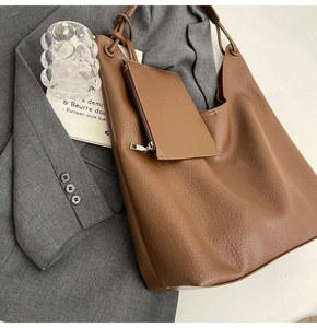 Détail du grand sac cabas marron avec texture de cuir litchi et petite pochette zippée