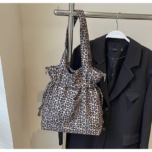 Detail view of the drawstring closure and front pocket on the leopard print tote bag