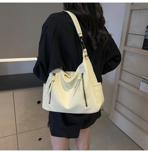 Detail of a large creamy white tote bag with lychee texture and dual vertical zipper pockets