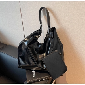 Detail of glossy black patent leather shoulder bag with matching mini card pouch and silver zipper