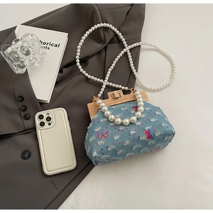 Detail of denim bag with sequin butterfly embroidery and elegant pearl handles