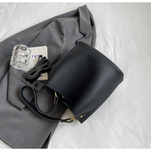 Vue détaillée du sac seau en cuir grainé noir avec des finitions dorées élégantes