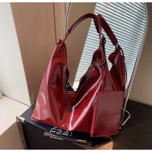 Detail of dark red glossy patent leather hobo bag with matching mini pouch charm