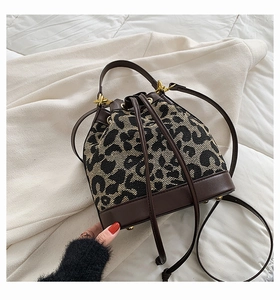 Detailed view of leopard print bucket bag with drawstring closure and metal feet