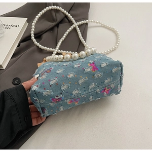 Detail of distressed denim mini bag with butterfly sequins and pearl strap handle