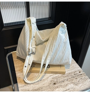 Detail der weißen Plissee-Hobo-Bag mit silbernen Metallösen und verstellbarem Gurt