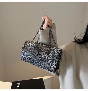 Détail d'un sac baguette léopard avec rivets métalliques et bandoulière chaîne