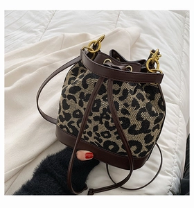 Detail of leopard print bucket bag with brown leather trim and retro gold hardware