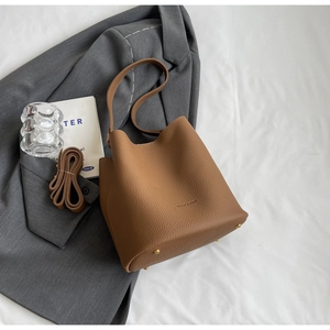 Détails d'un sac seau en cuir marron grainé avec clous dorés et deux bandoulières