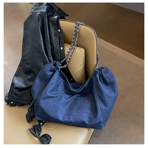 Detail of hobo denim tote bag with silver chain strap and stylish drawstring on a seat