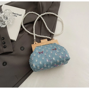 Detailed shot of denim crossbody bag featuring pearl strap and colorful butterfly embroidery