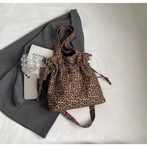 Detail of leopard print canvas bag featuring drawstring closure and adjustable strap