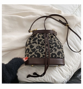 Detail of leopard print bucket bag with drawstring closure and golden protective feet