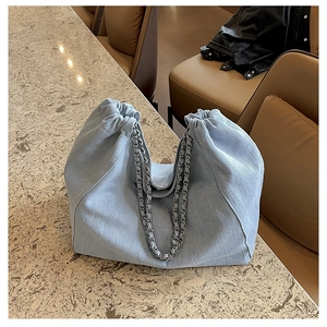 Close-up of light blue denim tote bag with chain strap and drawstring closure