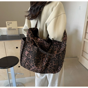 Grande borsa tote in tela leopardata sulla spalla del modello per uso quotidiano