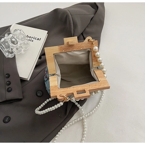 Detail of floral embroidery on denim shell bag with wooden frame and pearl strap