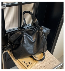 Detail of black faux leather tote bag with metal star rivet and detachable strap
