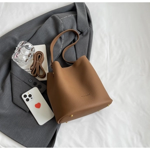 Détail d'un sac seau en cuir marron grainé avec rivets de protection dorés au fond