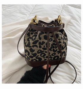 Detailed close-up of leopard print bucket bag with leather drawstring and gold hardware