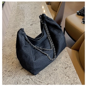 Detailed shot of large capacity denim tote with silver chain and drawstring texture