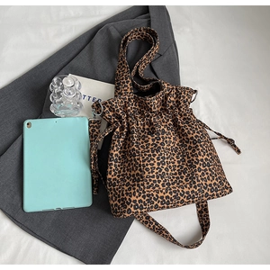 Detail of leopard print canvas tote bag with drawstring side and adjustable shoulder strap