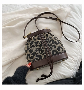 Detail view of leopard print bucket bag with drawstring closure and golden metal feet