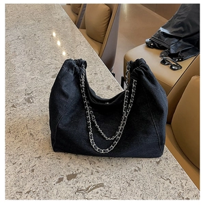 Detail of black denim hobo bag with silver chain straps and drawstring closure
