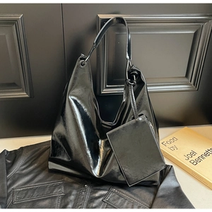 Detail of glossy black hobo bag with matching mini pouch and smooth leather texture