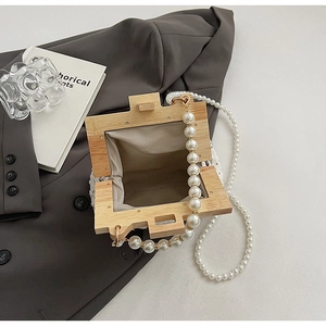 Detail of wooden frame handbag featuring large white pearl handle and woven lining