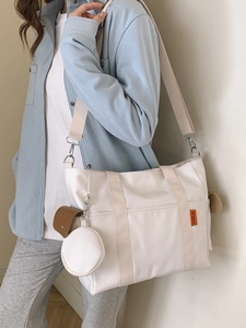 White nylon tote bag with wide shoulder strap and small round pouch for casual daily wear