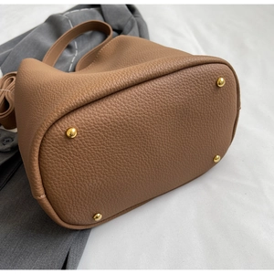 Détail de la base du sac seau en cuir marron avec quatre clous de protection en métal doré